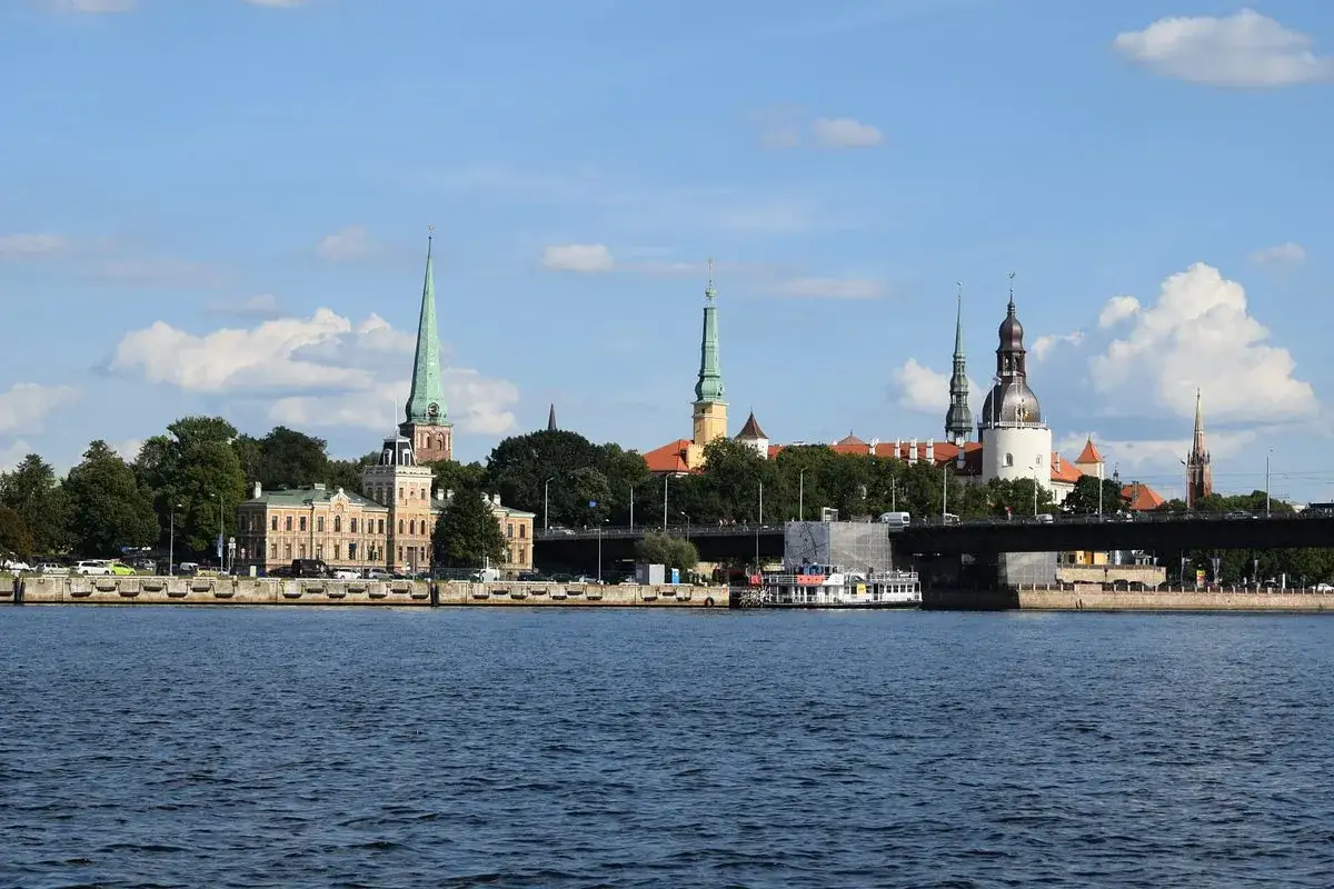 Blick auf den Rigaer Hafen mit Kirchtürmen und Gebäuden am Ufer, eine Brücke überspannt den Fluss.