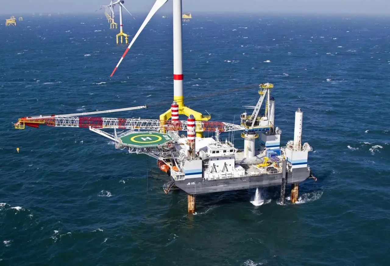 Ein Jack-up-Schiff mit Kran und Hubschrauberlandeplatz im Meer, umgeben von Windkraftanlagen.