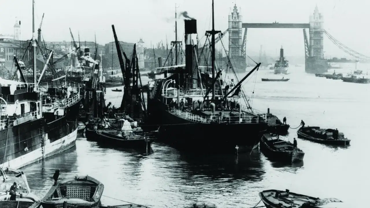 Dampfschiffe und Kr&auml;ne im gesch&auml;ftigen London Harbour. Im Hintergrund ragt die Tower Bridge empor.
