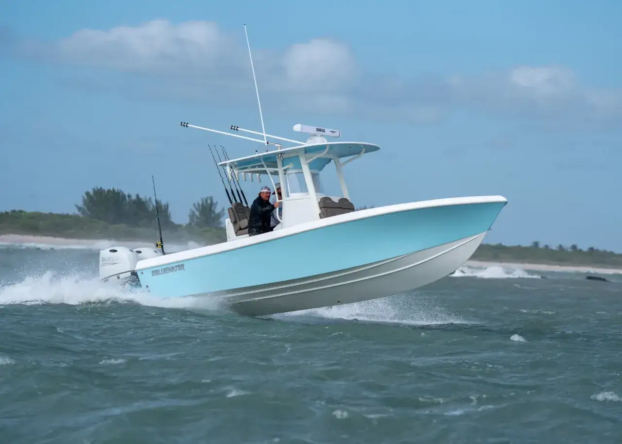 Ein hellblau-wei&szlig;er Katamaran mit zwei Au&szlig;enbordmotoren f&auml;hrt schnell &uuml;ber das Meer. Angler stehen an Bord.