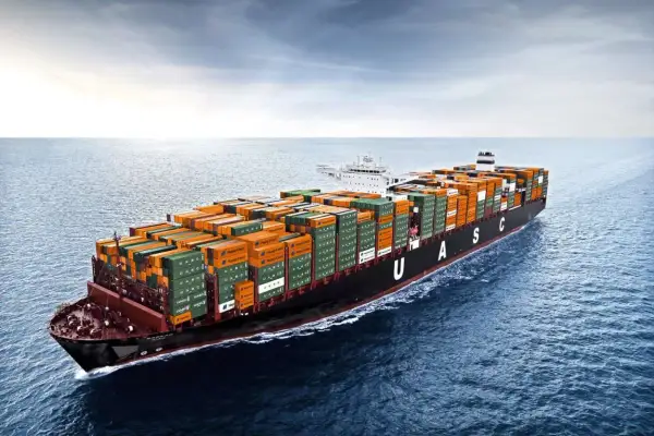 Ein riesiges Containerschiff mit orangefarbenen und grünen Frachtcontainern fährt auf dem Meer. Die UASC-Schriftzüge sind gut sichtbar. Die globale Logistik ist auf dem Weg, die Transitzeit zu optimieren.