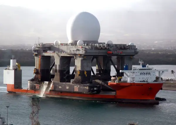 Die orangefarbene "Blue Marlin" ist ein Schwergutfrachter, der eine riesige Plattform mit einer großen weißen Kuppel transportiert.