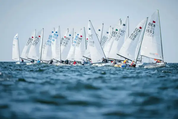 Viele Boote segeln bei der Kieler Woche. Die weißen Segel sind mit Länderkürzeln und Nummern beschriftet.
