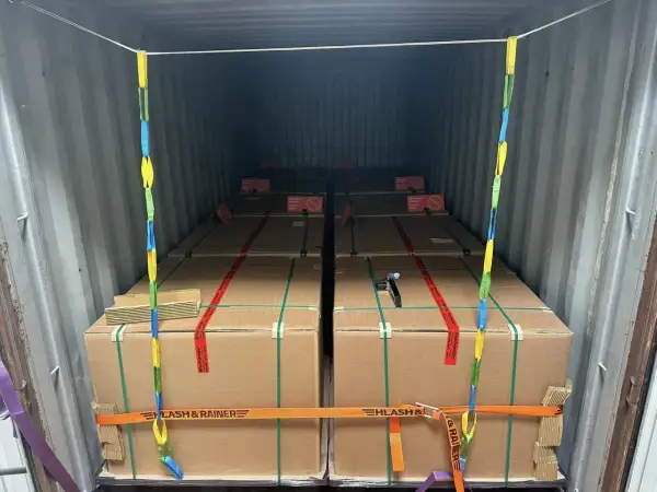 Ladungssicherung in einem Frachtcontainer: Mehrere große Kartons, gesichert mit Gurten und Ketten. Verschiedene Arten von Containern werden hier für den Transport genutzt.