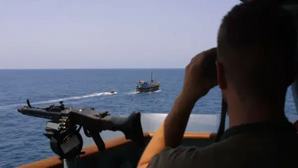 Mann mit Fernglas beobachtet ein Schiff, während ein Maschinengewehr bereitsteht. Möglicherweise ein Einsatz von Smit Salvage.