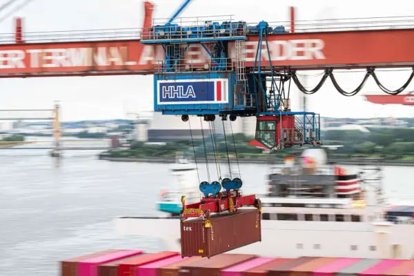 Ein großer Kran hebt einen Container im Mumbai Port. Die HHLA-Beschriftung ist auf dem Kran zu sehen.
