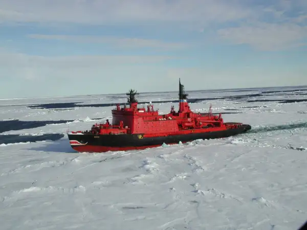 Ein rotes Eisbrecher-Schiff mit Haifischzähnen am Bug kämpft sich durch gefrorenes Wasser.