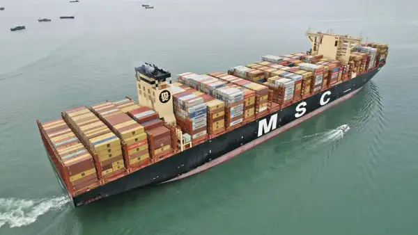 Die MSC Irina, ein riesiges Containerschiff, transportiert Fracht über das Meer. Ein kleines Beiboot fährt nebenher.