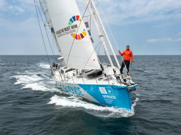 Mann auf Segelboot der Malizia Ocean Race mit Botschaft "A race we must win - Climate Action Now!".