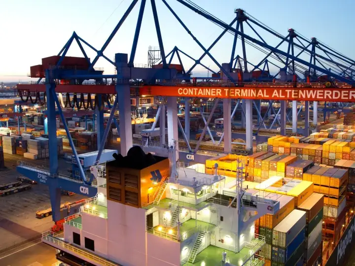 Containerhafen Altenwerder bei Dämmerung. Kräne und Containerstapel, die auf die **spot rates** für den globalen Handel warten.